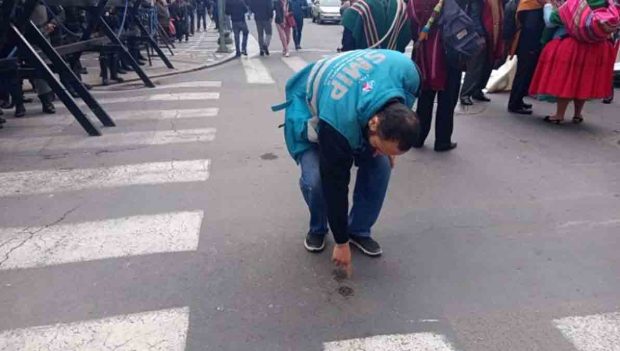 un funcionario municipal muestra el daño provocado en el asfalto por la explosión de dinamita