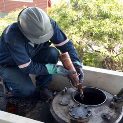 personal de YPFB realiza prueba de calidad de la gasolina en un tanque de almacenamiento