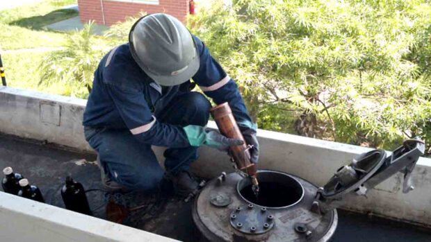 personal de YPFB realiza prueba de calidad de la gasolina en un tanque de almacenamiento