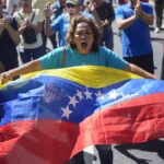 una mujer con una bandera venezolana en una protesta callejera