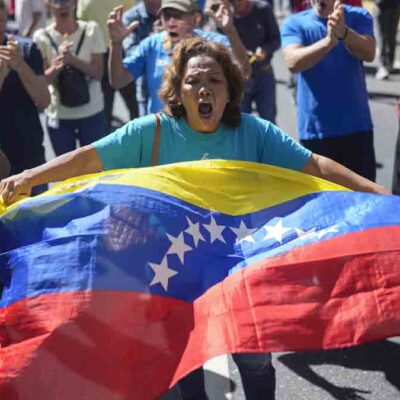 una mujer con una bandera venezolana en una protesta callejera