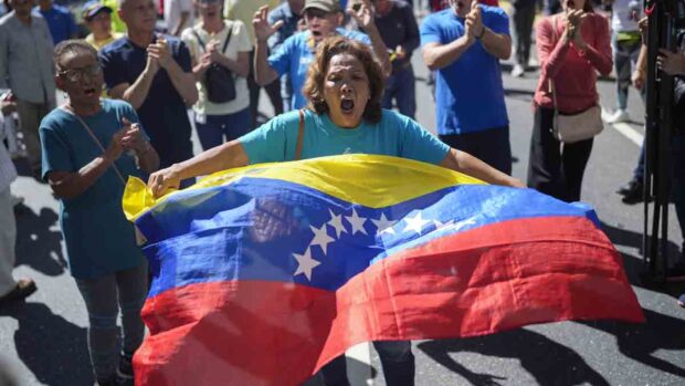 una mujer con una bandera venezolana en una protesta callejera