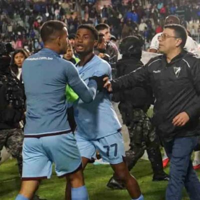 un jugador de Bolívar es contenido por uno de sus compañeros