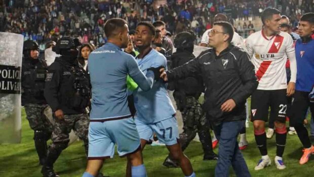 un jugador de Bolívar es contenido por uno de sus compañeros